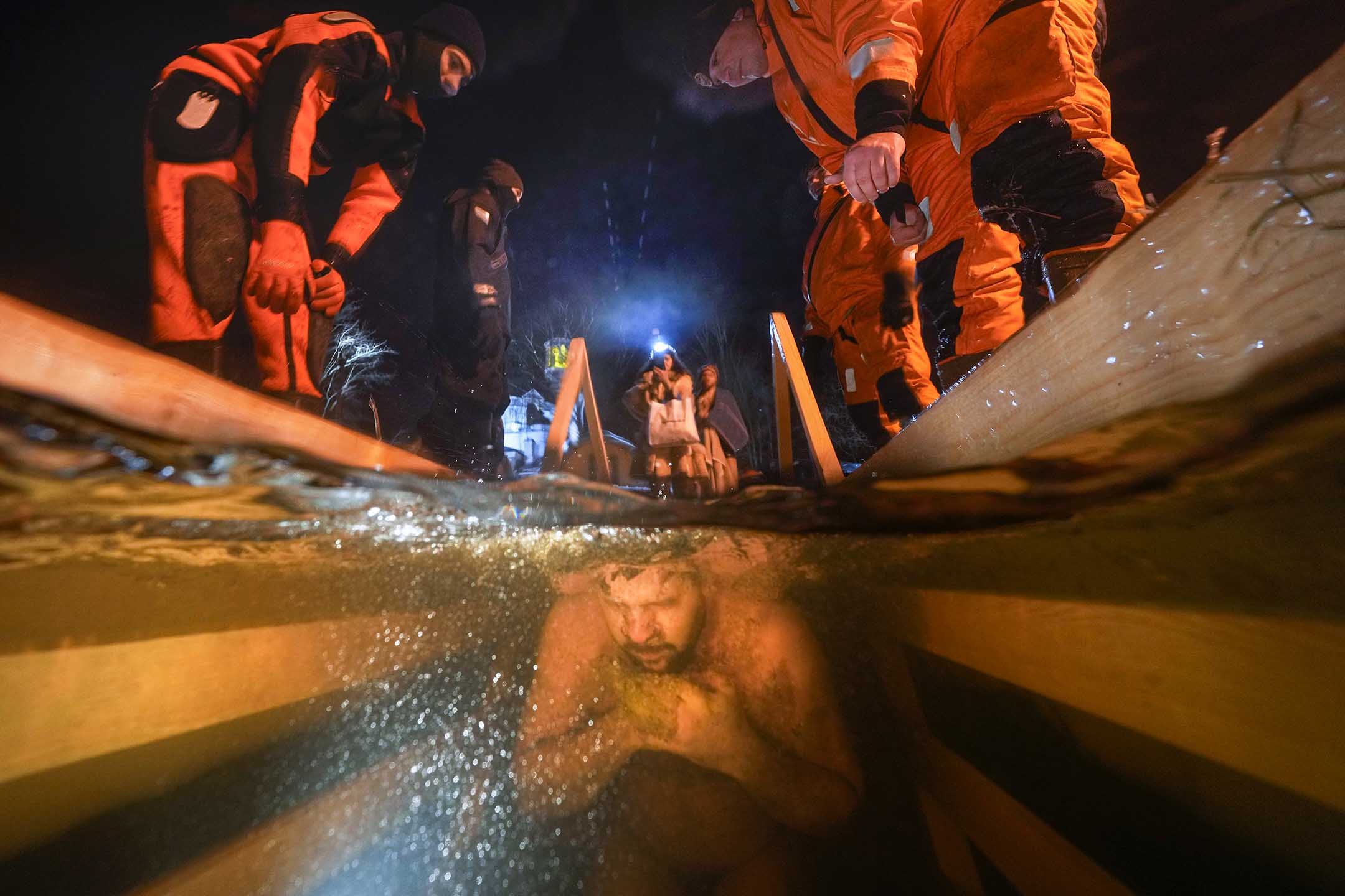 2022年1月18日，俄罗斯圣彼得堡举行的传统主显节活动中，救援人员在旁观察一名浸入冰水中的东正教信徒。