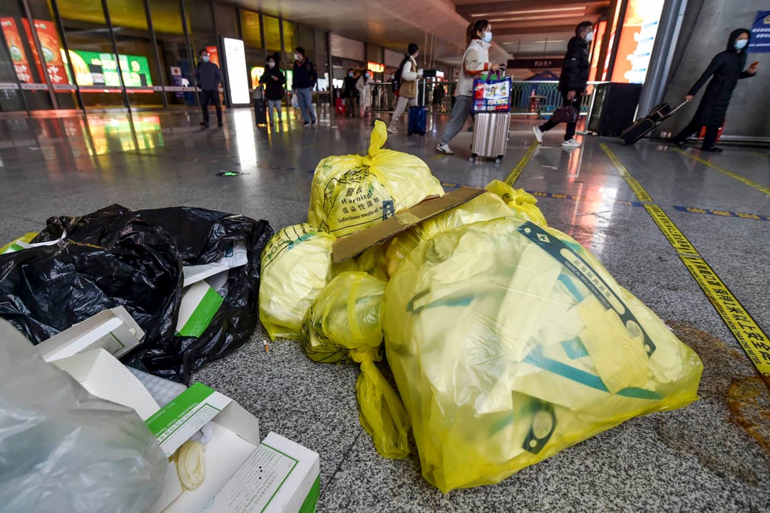 2022年12月7日,中国南京,高铁南京南站内的乘客走过暂放在地上的医疗废料。