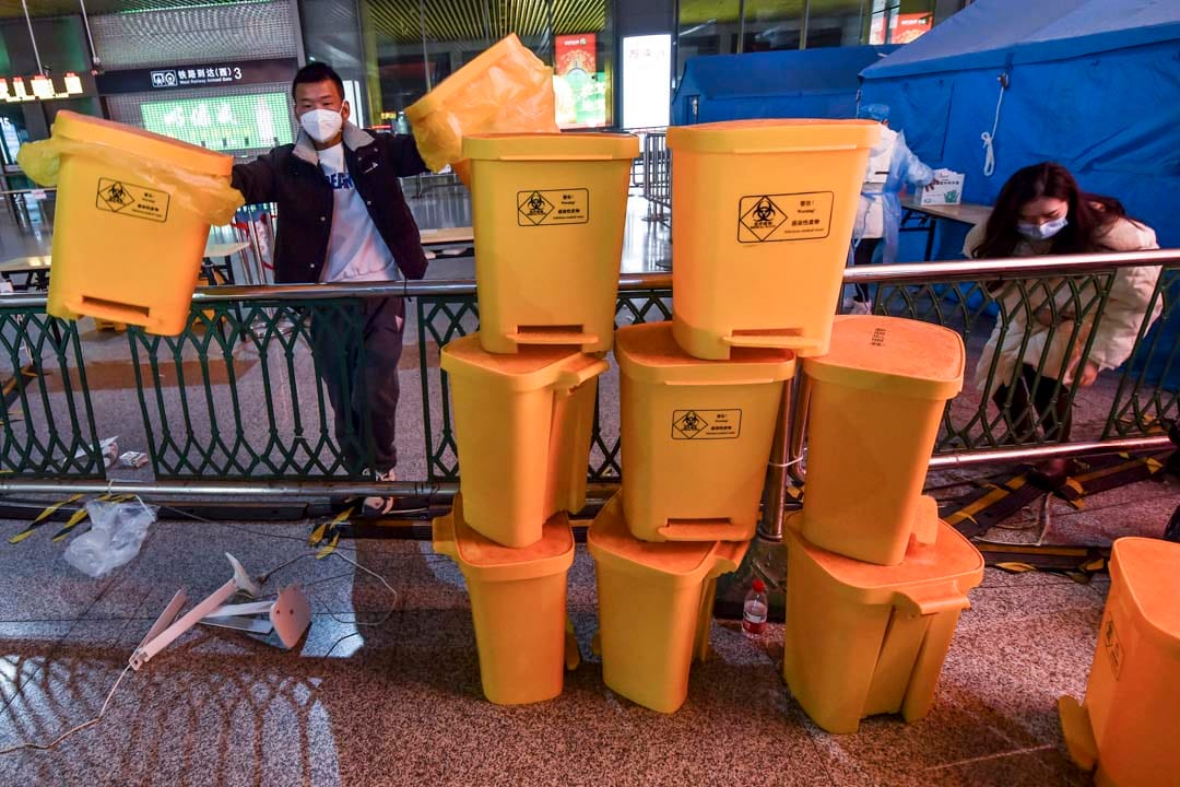 2022年12月7日,中国南京,工作人员在清理高铁南京南站内的医疗废料桶。