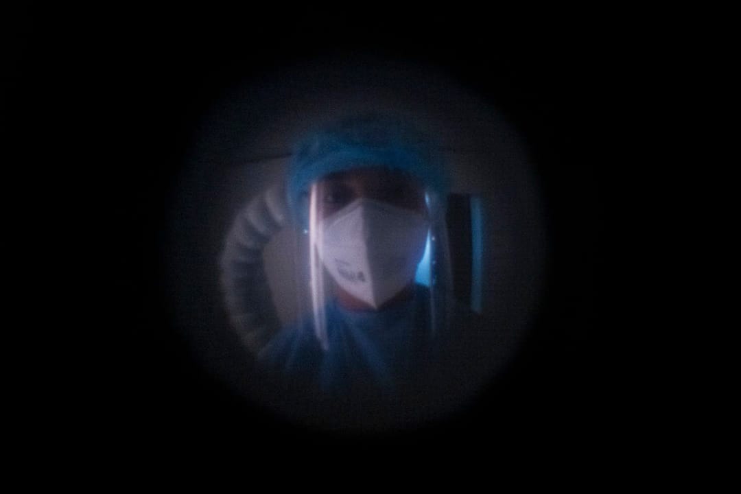 2022年5月9日，一名身穿 PPE 的酒店工作人员在政府指定的检疫酒店的房间外等候，对一名接受检疫命令的旅客进行核酸测试。