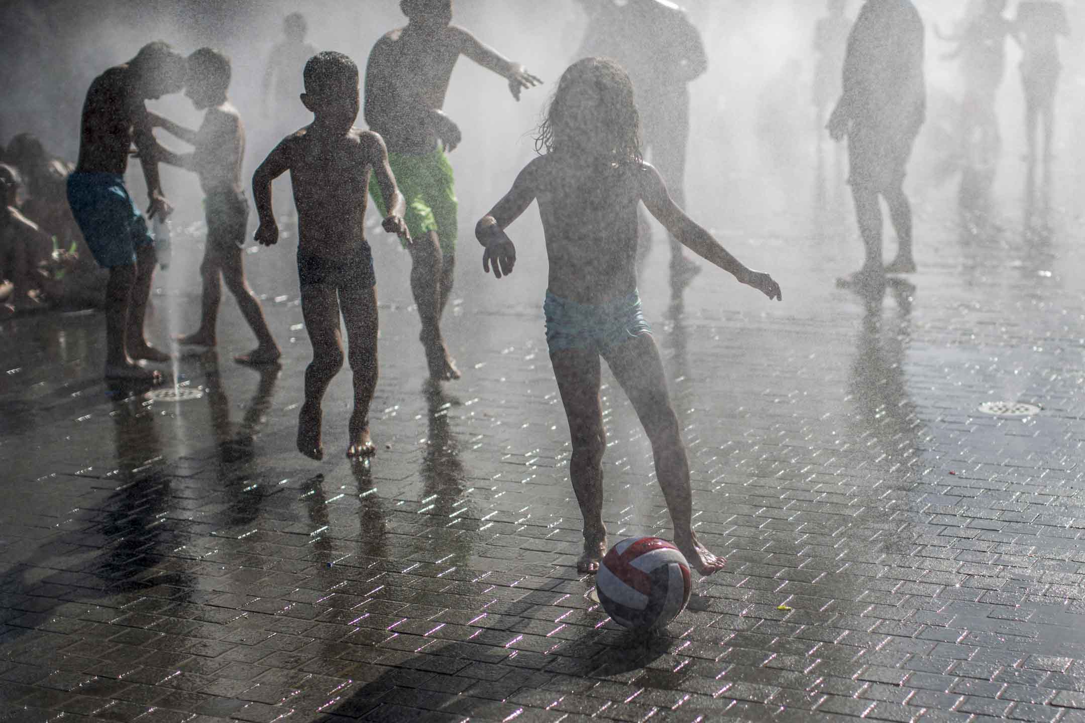 2023年7月9日,西班牙马德里,孩子们在喷水池中间玩乐。摄:Luis Soto/SOPA Images/LightRocket via Getty Images