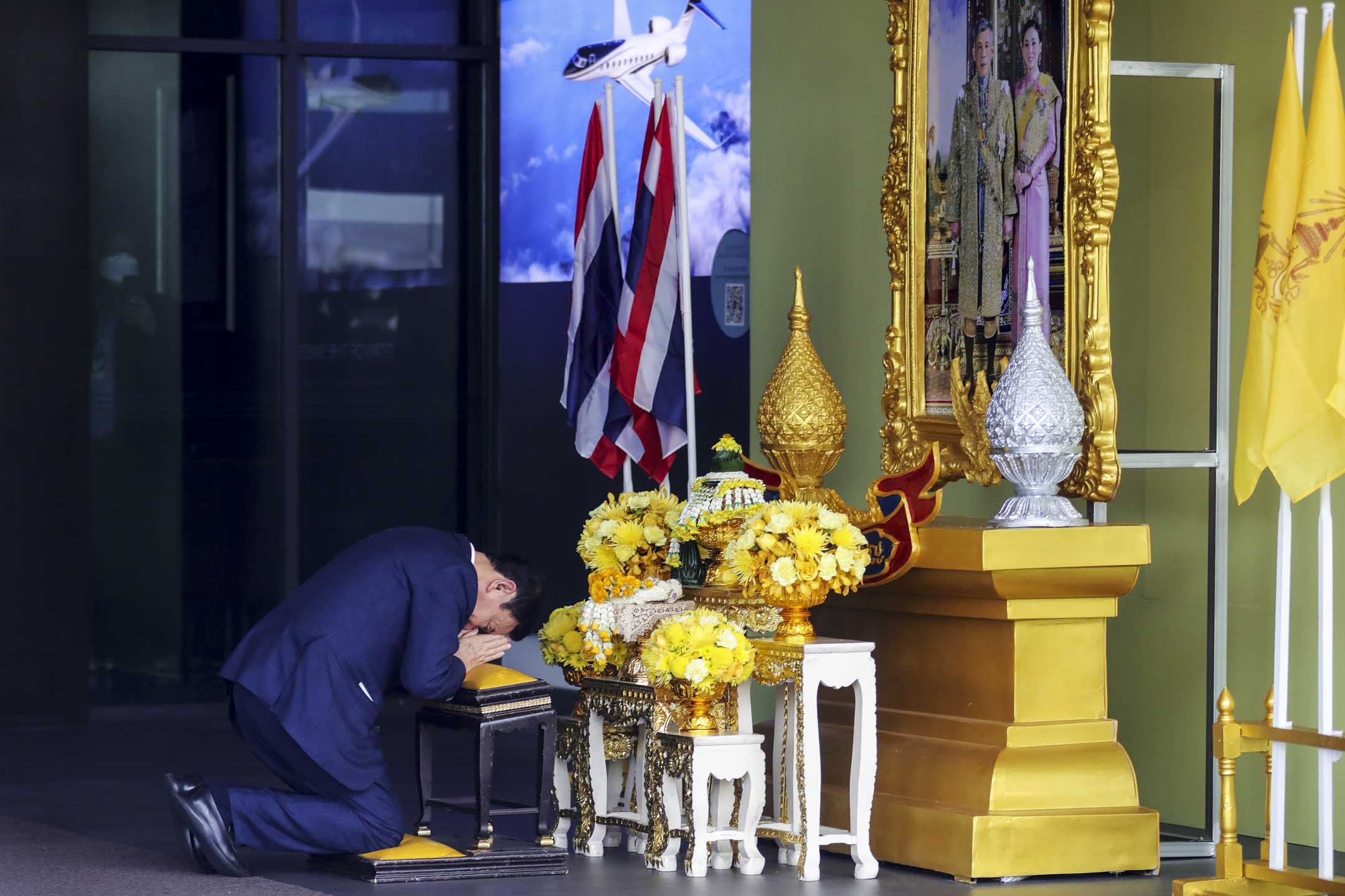 2023年8月22日,泰国前总理他信抵达泰国曼谷廊曼国际机场,向泰国国王与王后的肖像鞠躬。摄:Lauren DeCicca/Getty Images