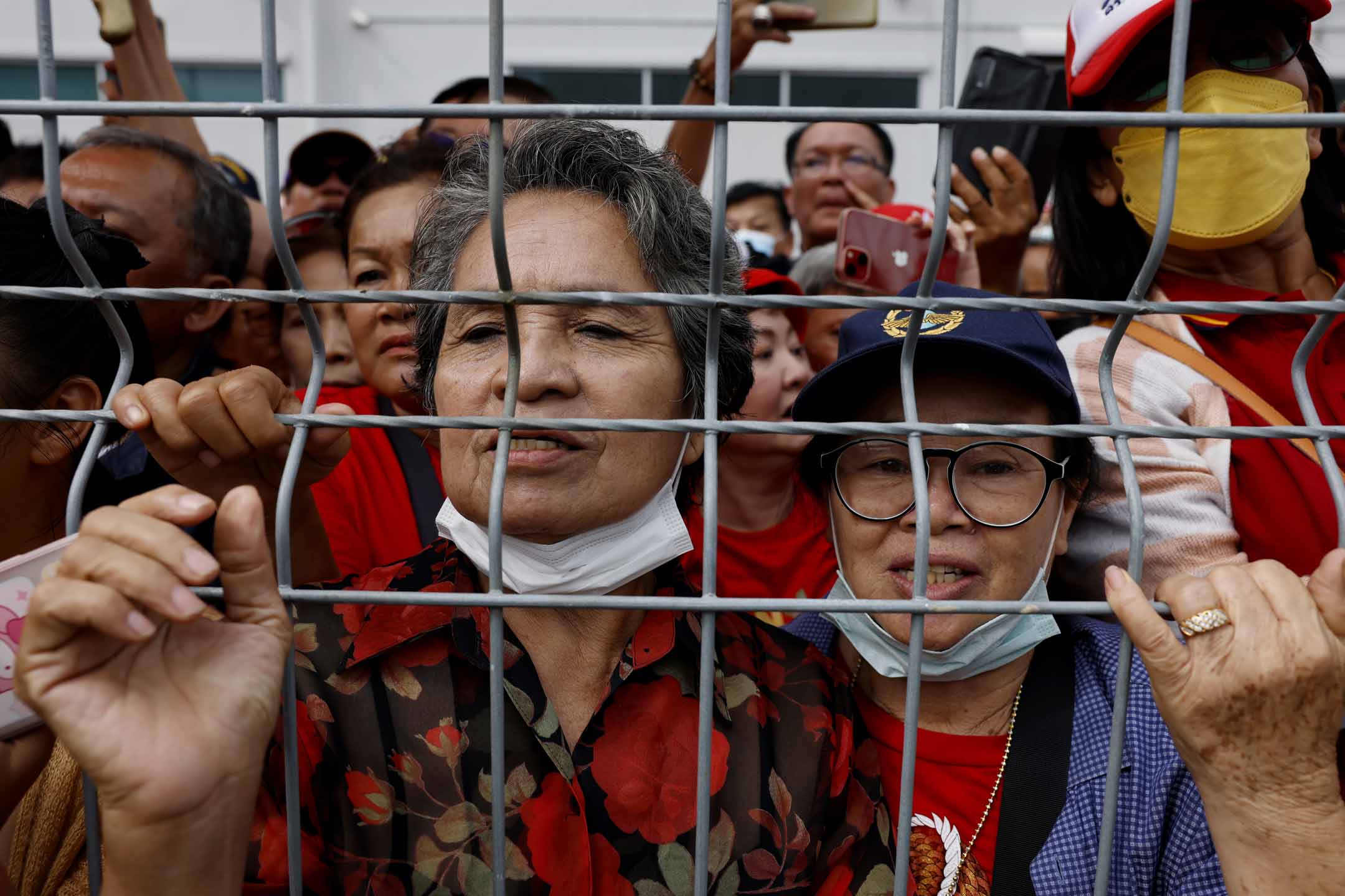 2023年8月22日,他信的支持者聚集在泰国曼谷廊曼国际机场外,聚集在栅栏后面,等待到来。摄:Lauren DeCicca/Getty Images