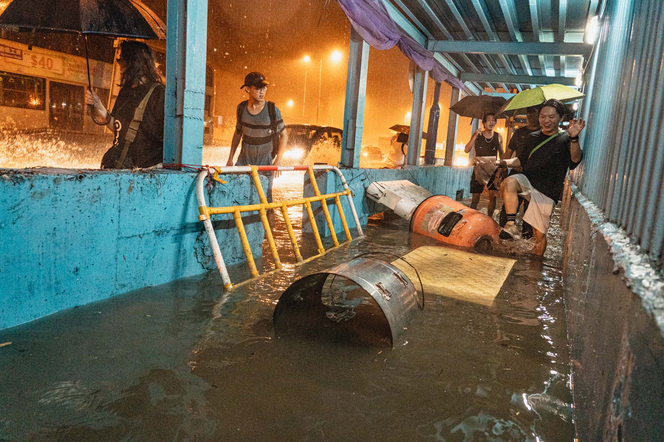 2023年9月8日，自有紀錄以來最大暴雨，，有市民涉水而行，水面飄浮著圍欄、垃圾桶等雜物。攝：Ryan Lai/端傳媒