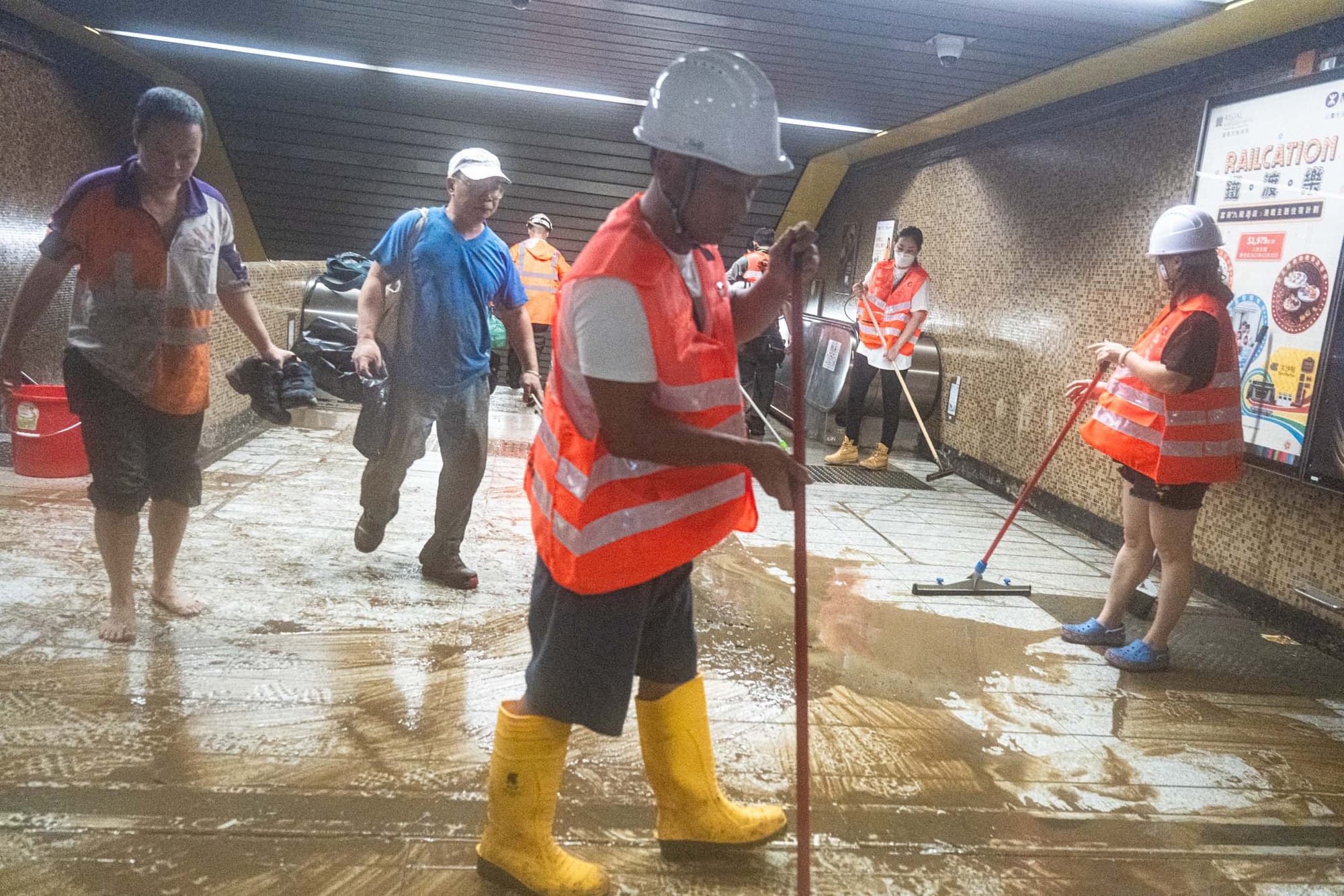 2023年9月8日，大水退去後，黃大仙港鐵職員在出口清理污泥。攝：Ryan Lai/端傳媒