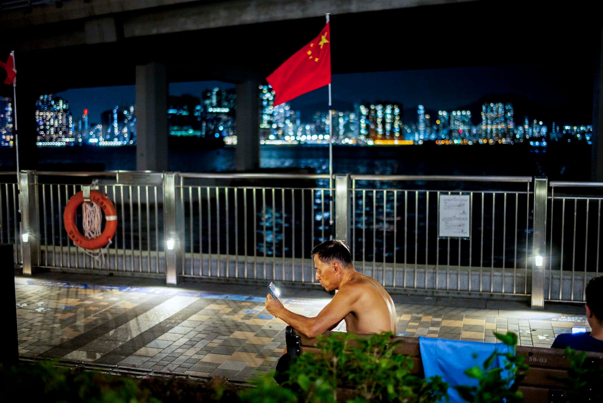 北角码头，一位脱去上衣的男士观看手机。摄：林振东/端传媒 