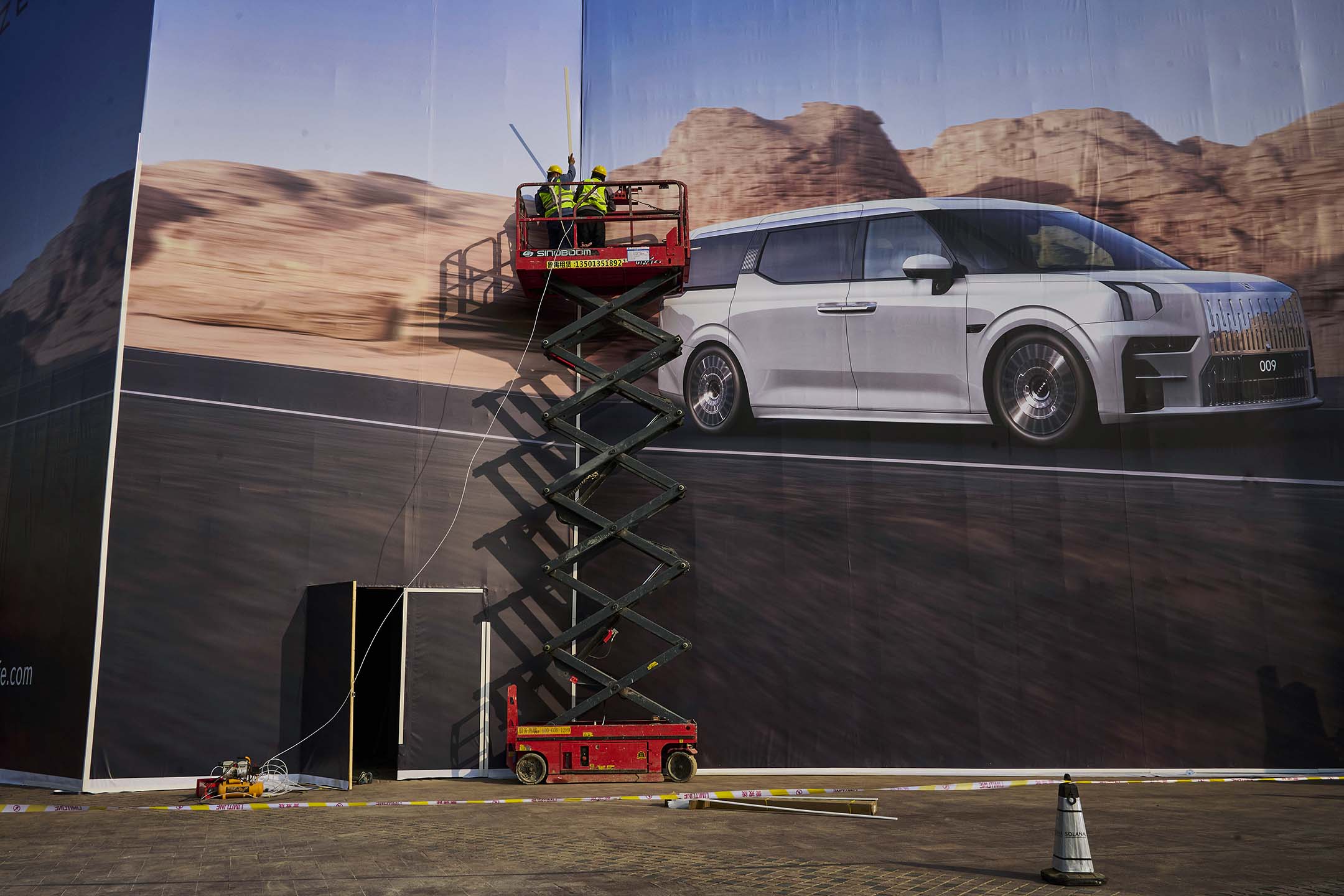 2023年3月31日,北京,工人們為中國電動車製造商安裝一塊大型廣告牌。攝:Kevin Frayer/Getty Images