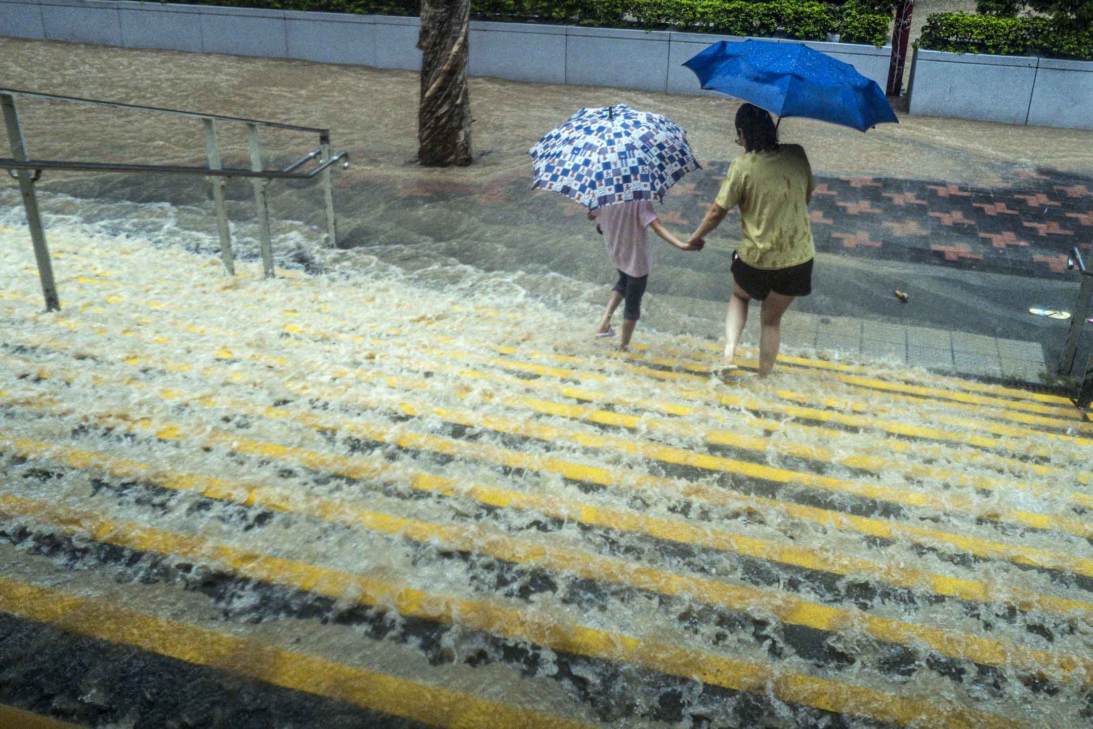 2023年9月8日，暴雨大來的洪水沖過地鐵站，市民在水中前行。攝：Lam Yik/Bloomberg via Getty Images