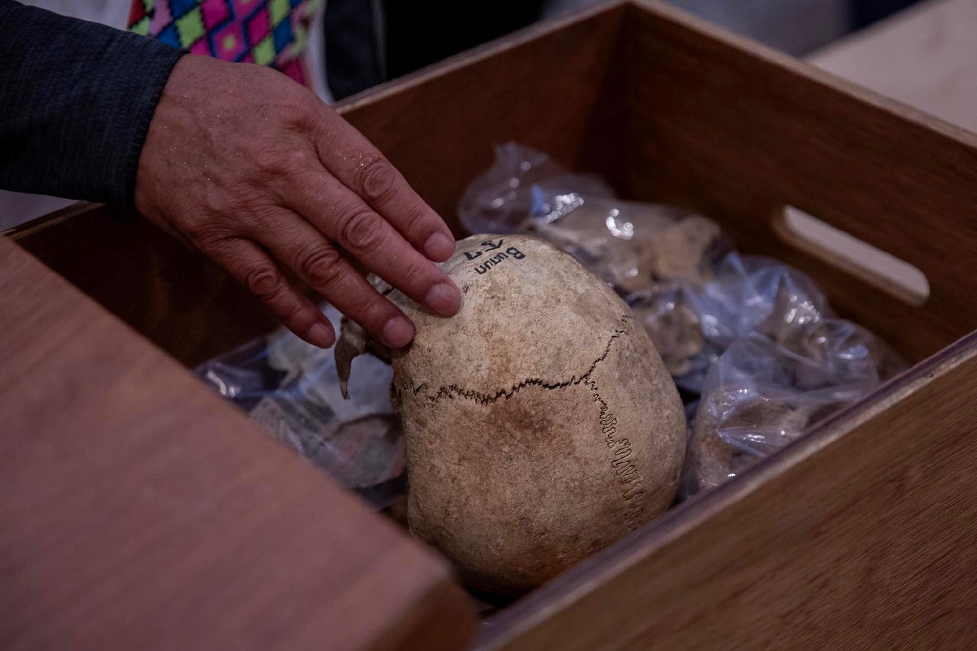 2023年11月15日,台大醫學院,馬遠部落的布農族人撫摸祖先遺骨。攝:陳焯輝/端傳媒