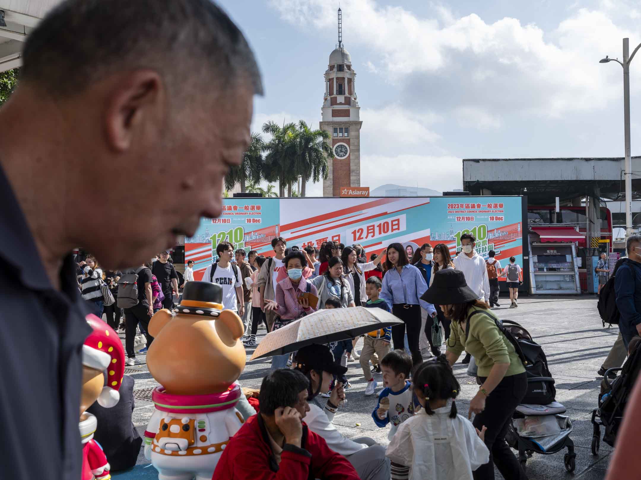 2023年12月9日，尖沙咀碼頭外有屏幕播放呼籲區議會投票的影片。攝：林振東/端傳媒