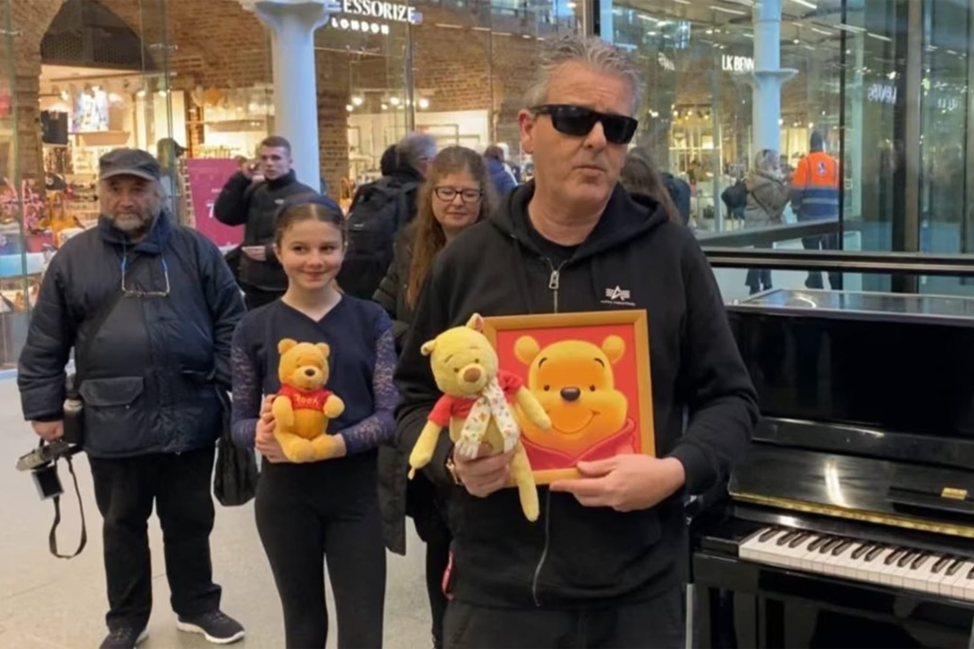 “伦敦车站钢琴冲突”事件后,英国钢琴家Brendan Kavanagh手持小熊维尼布偶到场。图:影片截图