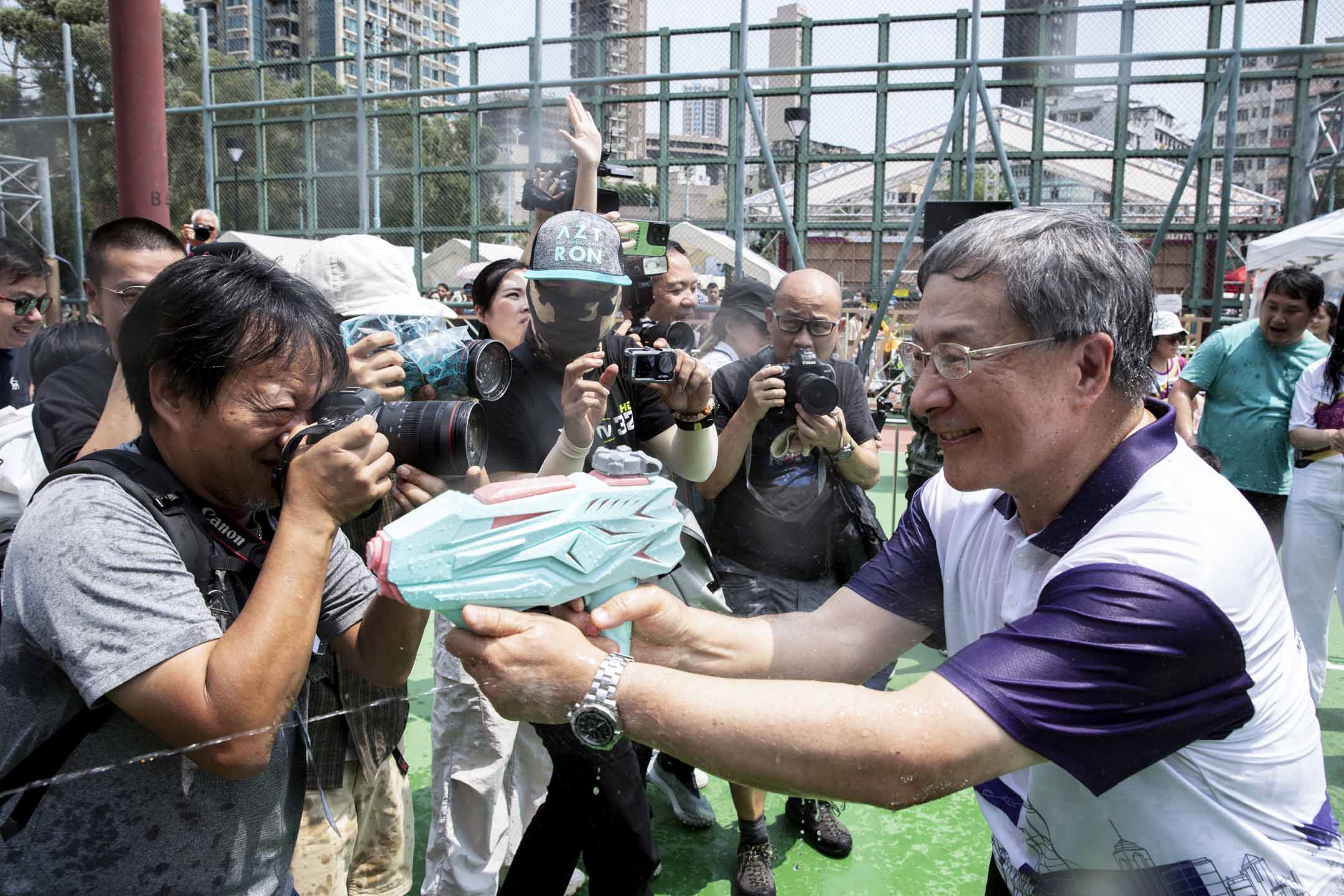 2024年4月13日，政務司副司長卓永興到籃球場與市民互相射水，期間有小朋友以水槍「追擊」卓永興。攝：林振東/端傳媒