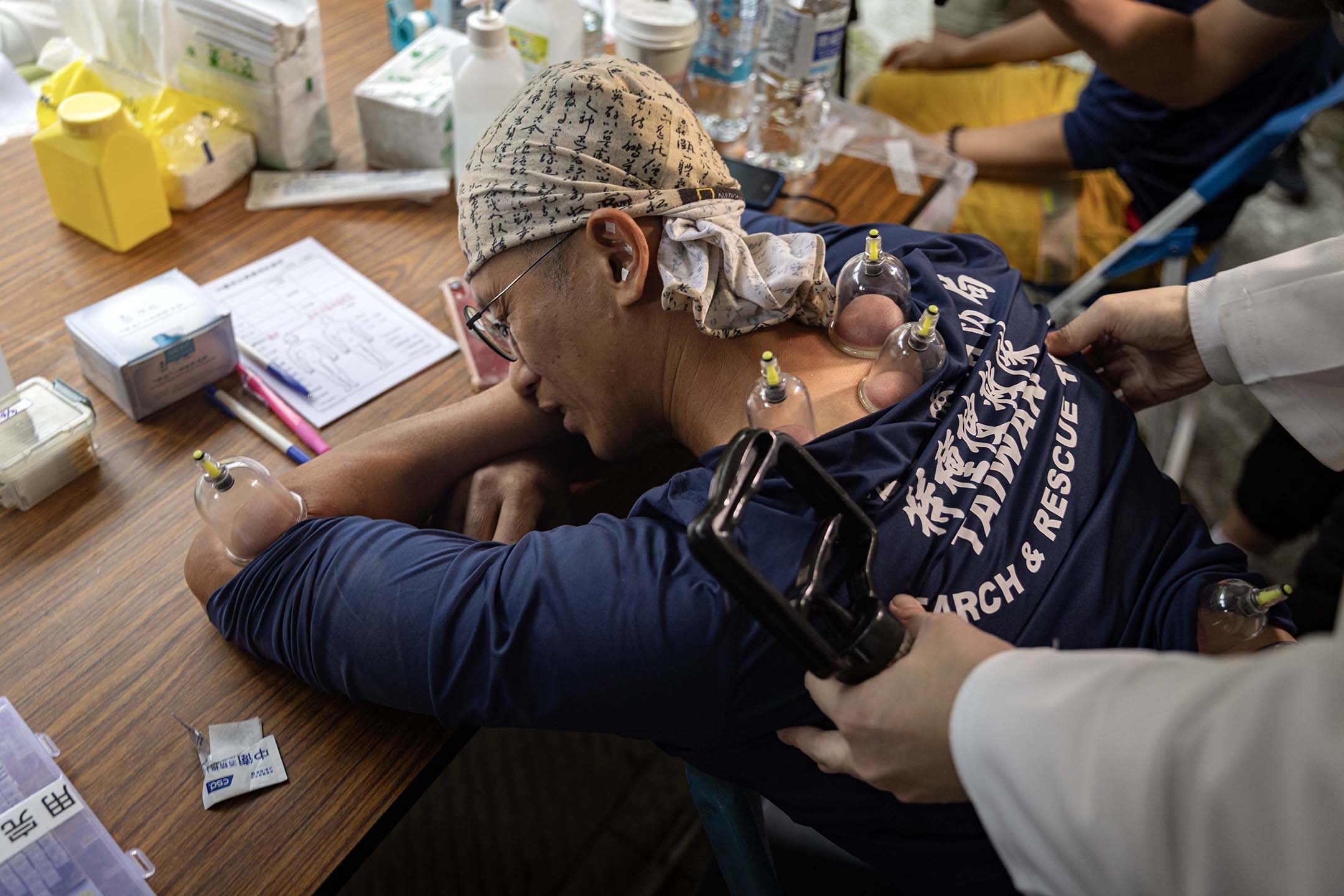 2024年4月5日,花蓮,一名醫師為疲累的救援人員拔罐。攝:陳焯煇/端傳媒