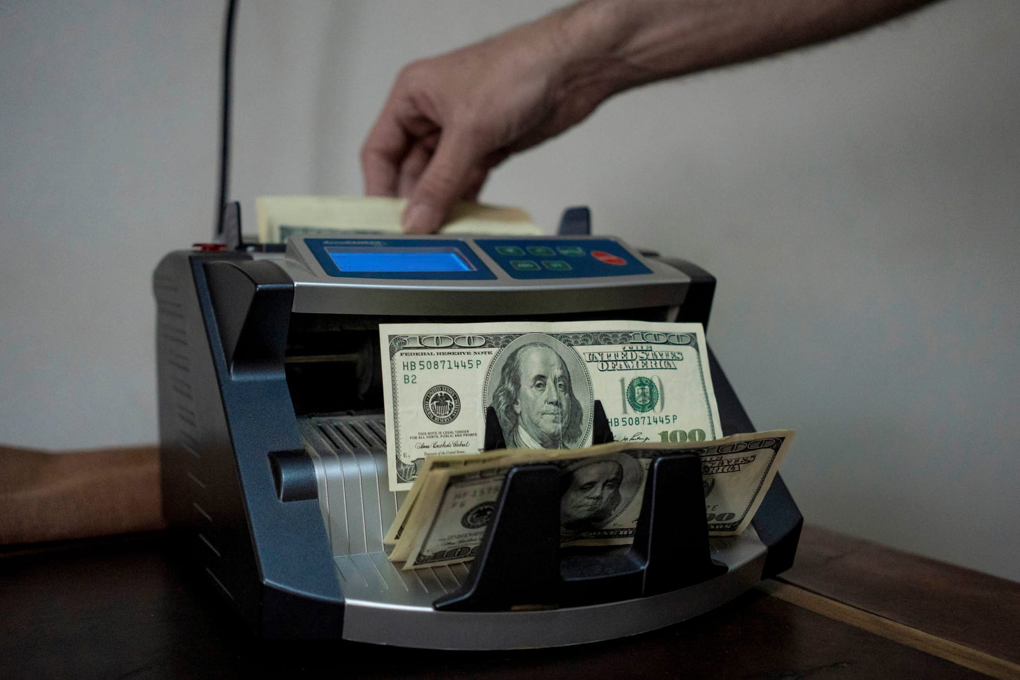 2024年1月10日，阿根廷布宜諾斯艾利斯的一家貨幣兌換所，一名工作人員使用點鈔機點鈔100美元紙幣。攝：Anita Pouchard Serra/Bloomberg via Getty Images