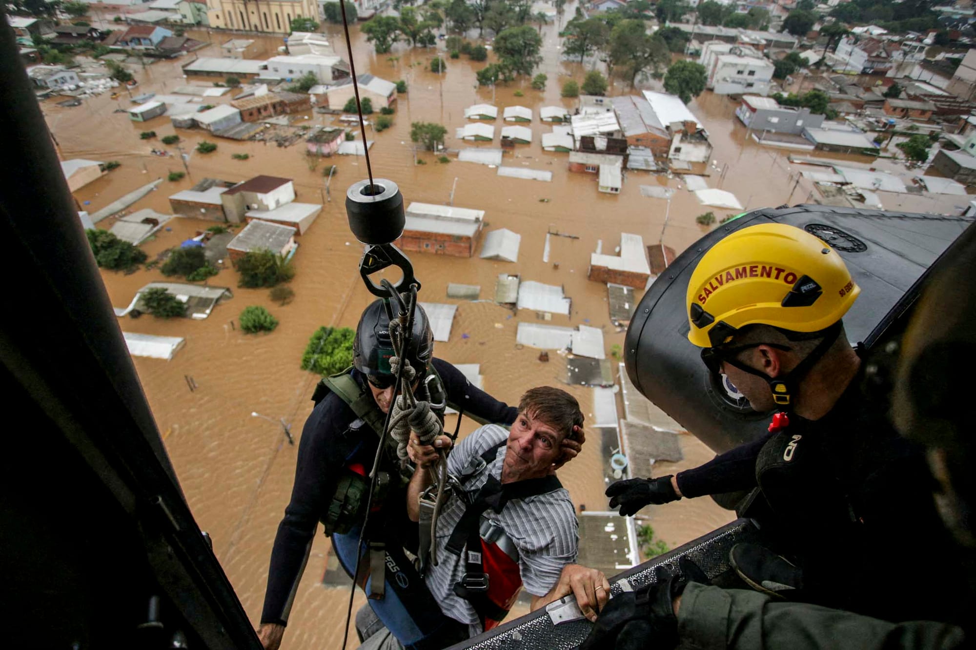 2024年5月4日，巴西南里奧格蘭德州卡諾阿斯發生洪水後，一名男子被軍事消防員救出。攝：Renan Mattos/Reuters/達志影像