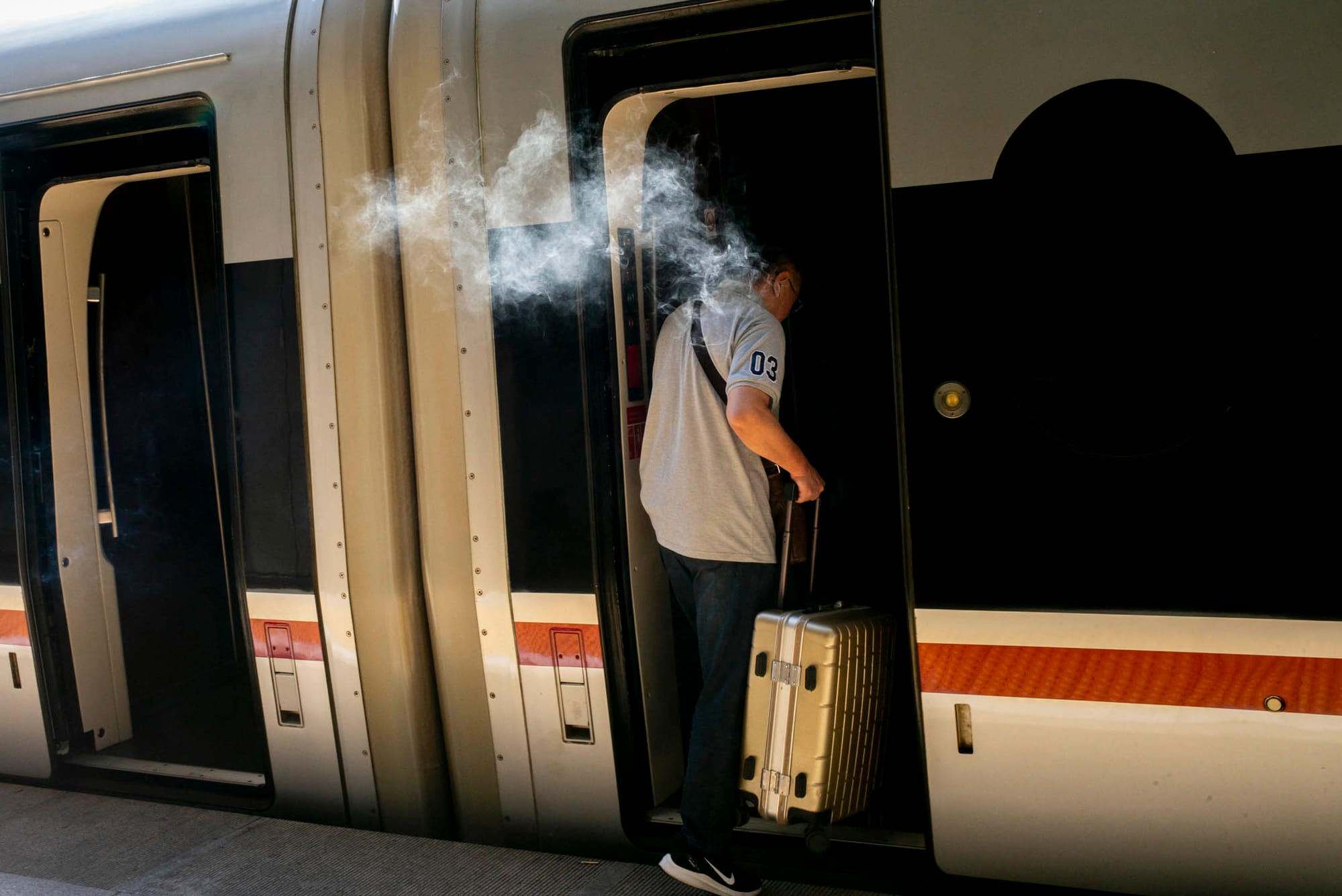 2023年8月29日，中国北京西站高铁月台，一名乘客登上开往河北的高铁前，抽最后一口烟。摄：林振东/端传媒