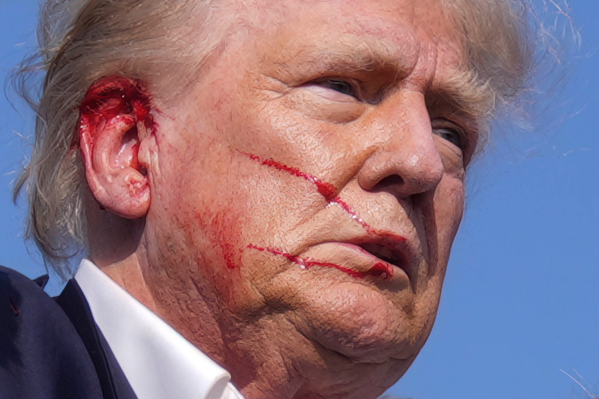 2024年7月13日，賓夕法尼亞州巴特勒，共和黨總統候選人、前總統特朗普在競選集會發表演講時，現場傳出疑似槍聲，被美國特勤局特工包圍離開，期間特朗普臉上有血。攝：Evan Vucci/AP/達志影像