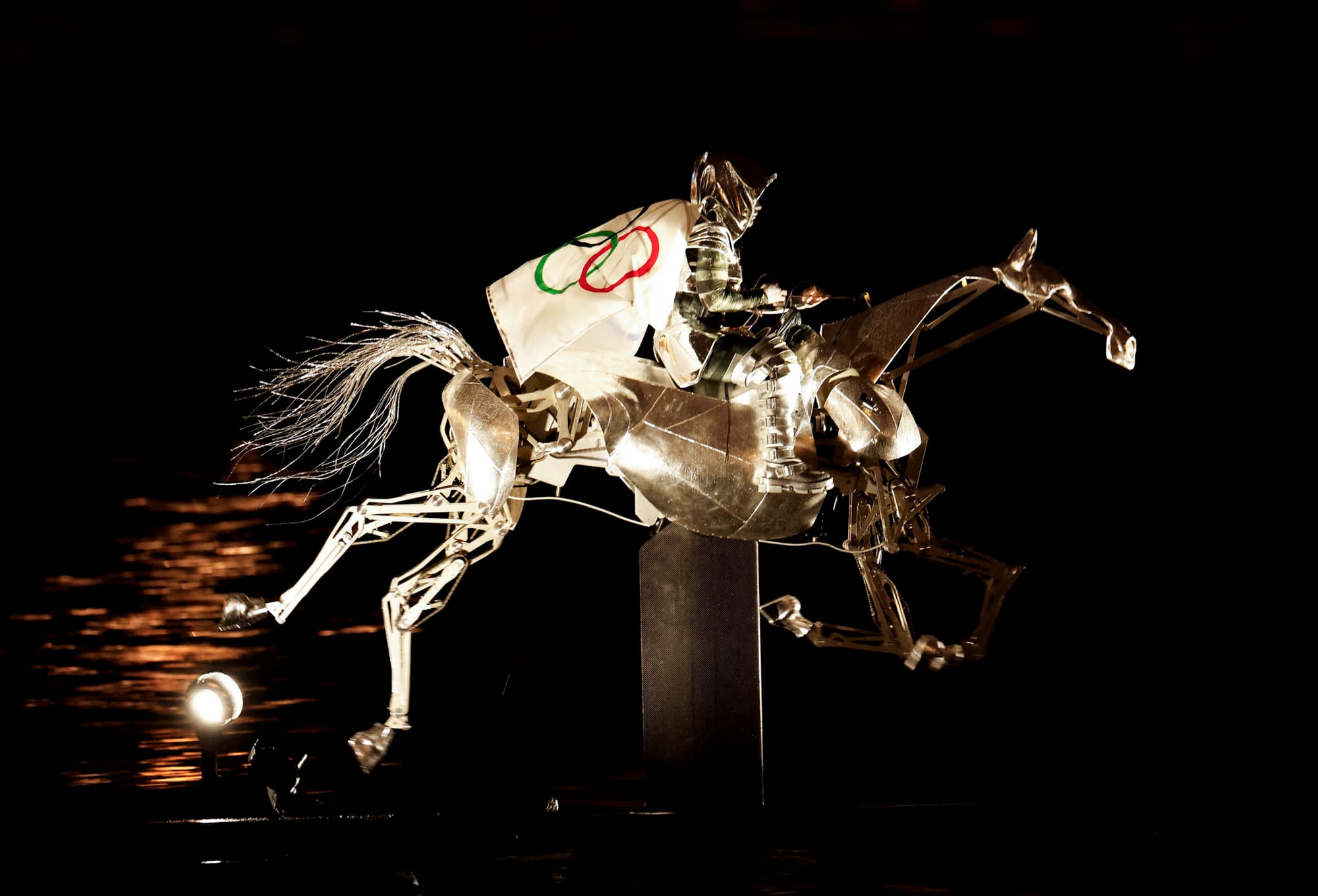 2024年7月26日，身著銀色盔甲、披上奧運會旗的女騎手穿梭過塞納河。攝：Adnan Abidi/Reuters/達志影像