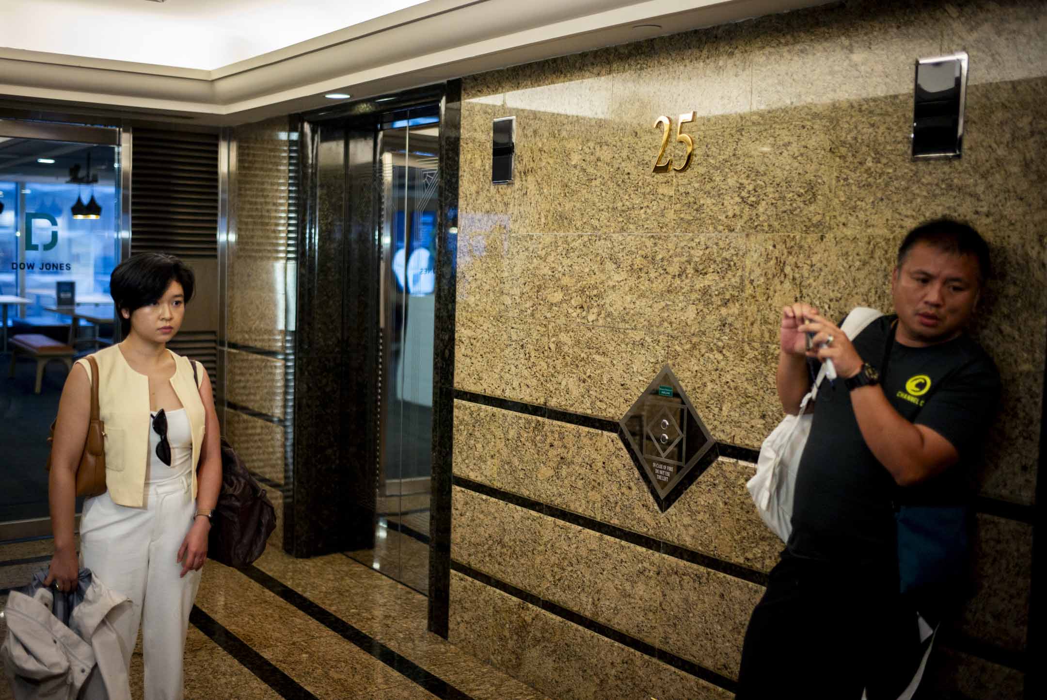 2024年7月17日，香港記者協會主席鄭嘉如遭《華爾街日報》辭退後，離開中環廣場的辦公室，被大批傳媒追訪，期間記協前主席陳朗昇亦在現場採訪。攝：林振東/端傳媒