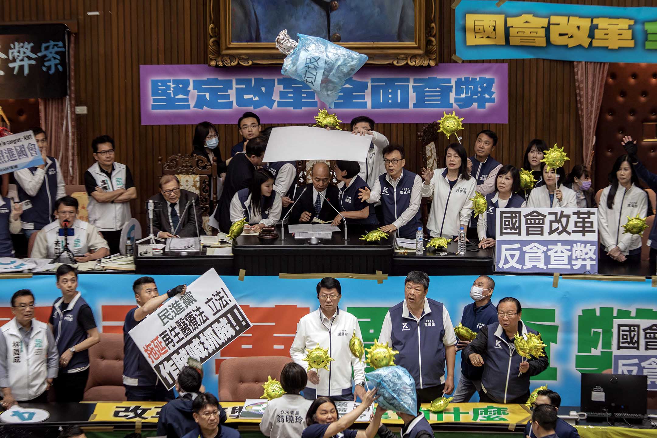 2024年5月28日，台北，立法院进行国会改革法案审议，立法院内民进党立委向主席台掉垃圾，国民党立委用看板阻挡保护立法院长韩国瑜。摄：陈焯煇/端传媒