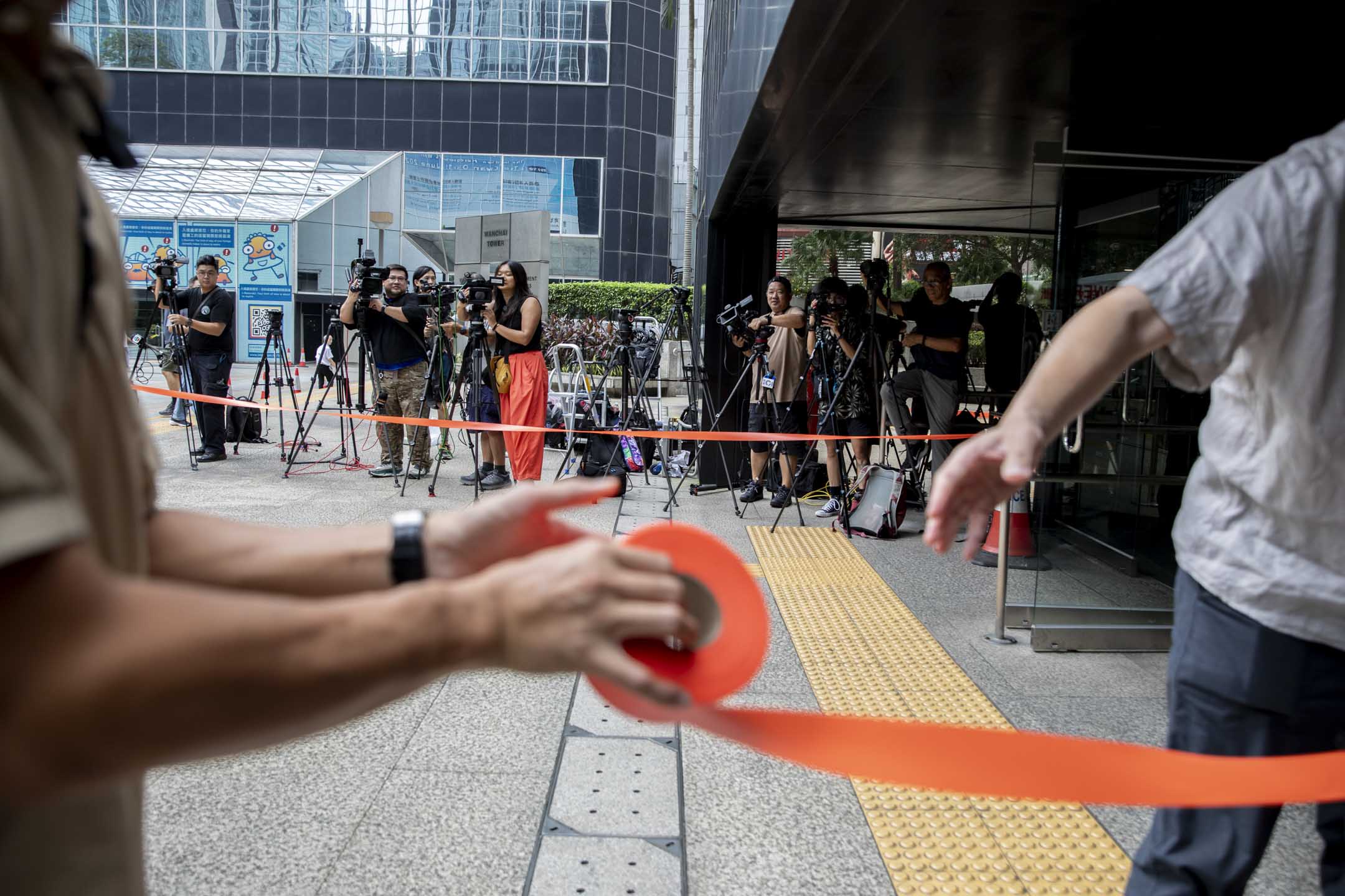 2024年8月29日,“立场新闻”母公司、前总编辑钟沛权、时任署任总编辑林绍桐被控串谋发布煽动刊物案在区域法院裁决,警方在法院外以橙带设置记者区。摄:林振东/端传媒