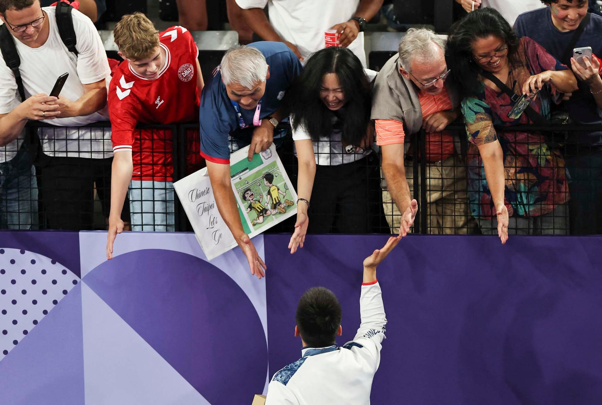 2024年8月4日,巴黎奥运羽毛球男子双打金牌由台湾代表团中华台北代表队李洋、王齐麟成功卫冕,场内跟支持者拍手。摄:Ann Wang/Reuters/达志影像