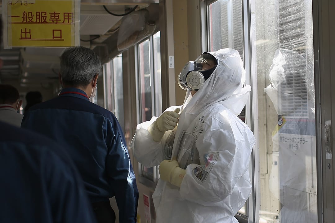 工作人员在进入核污染区前，在一座抗震建筑内换上保护衣物。摄:Christopher Furlong/GETTY