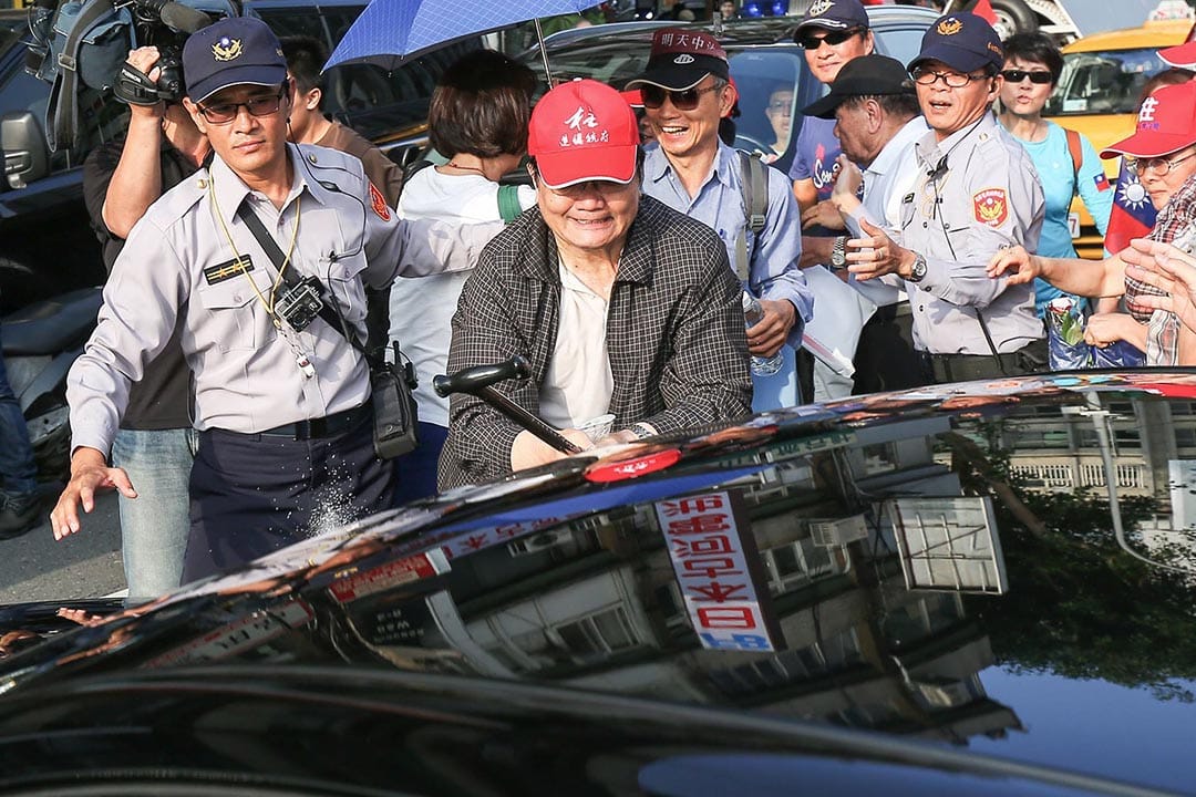 民眾持棍棒砸從黨中央駚出的車輛。攝 : 張國耀/端傳媒 