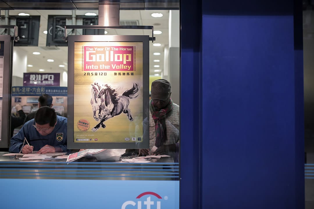 2014年，一位难民于投注站内投注。他来自刚果，因政治问题逃离刚果后辗转来到香港，获批确认为难民后一直未获转送至第三国，在香港滞留了十二年。摄: Billy H.C. Kwok/ 端传媒