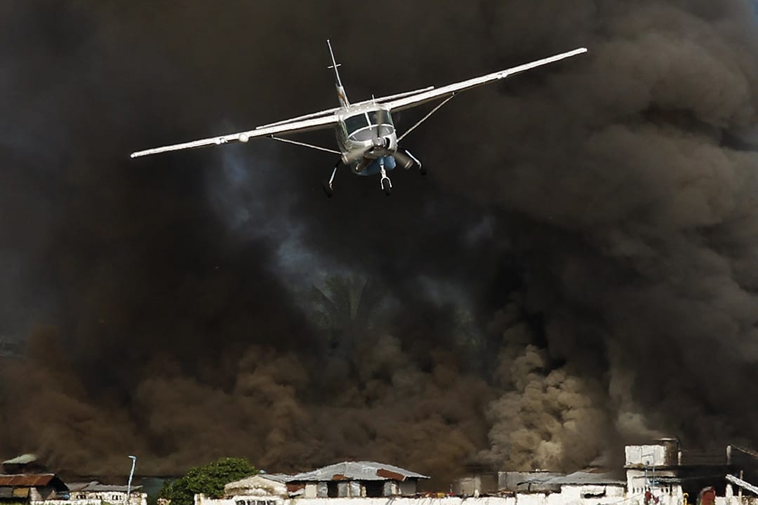 Kalay市的油站冒出大量黑烟，飞机接走部分灾民。摄: Soe Zeya Tun /REUTERS