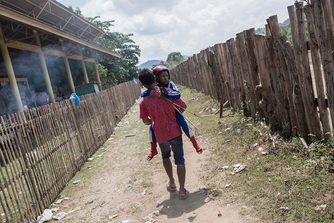 年仅九岁的小骑师在比赛中堕马弄伤脚部，唯有靠哥哥抱他往起跑线参与下一场比赛。摄：Putu Sayoga