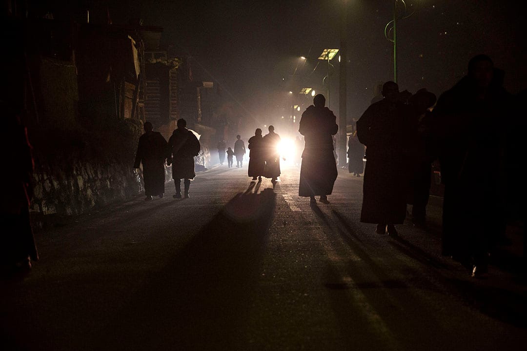 喇嘛們晚上離開佛學院，沿著黑暗的路回家。攝：Kevin Frayer/Getty Images