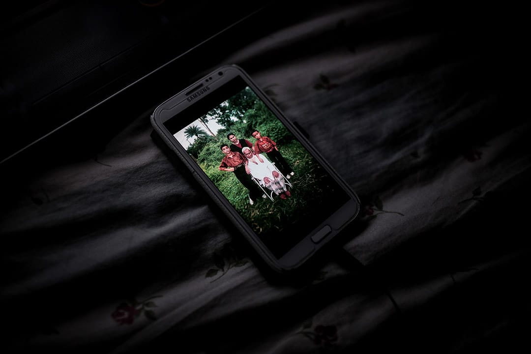 一位寻求庇护者手机里面的照片，照片是他年轻时与弟弟、母亲和祖父合照。摄: Billy H.C. Kwok/ 端传媒