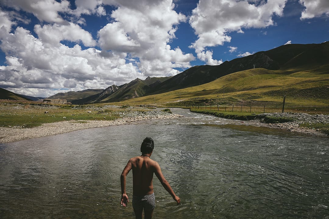 一名藏民青年在溪涧游泳。摄 : 王嘉豪/端传媒