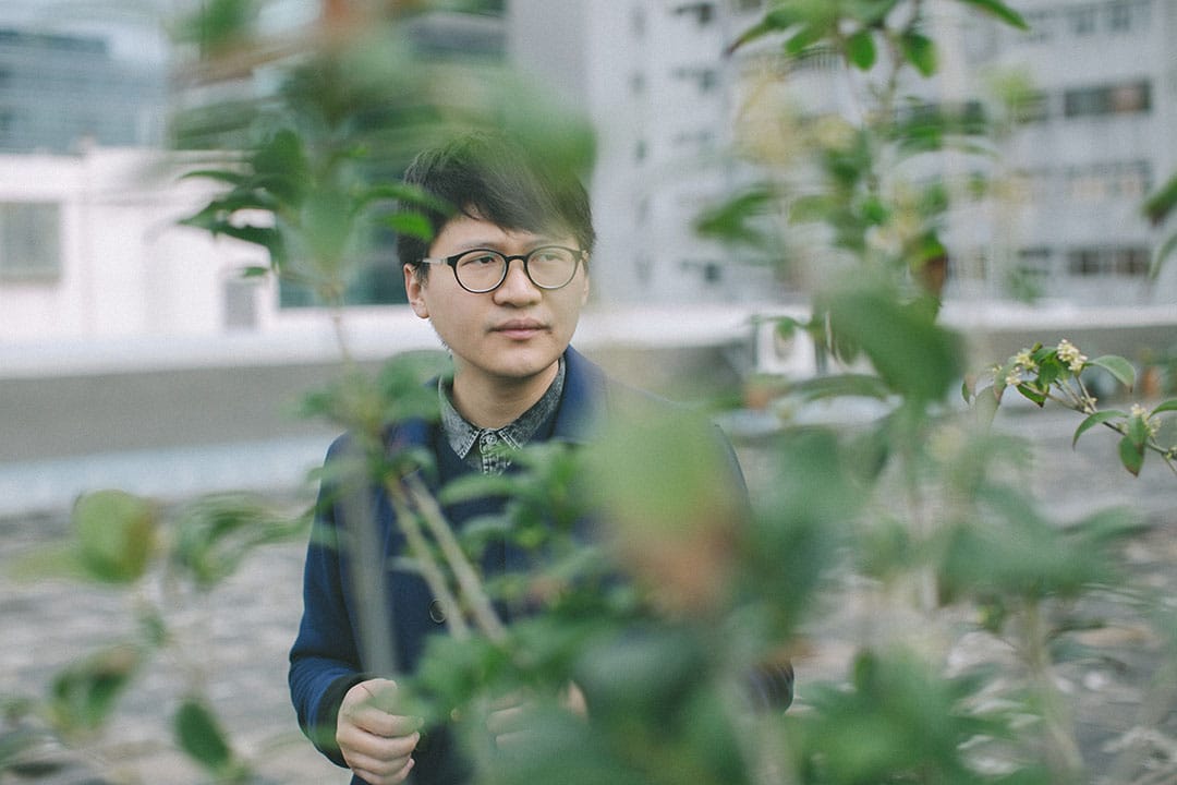 Trevor Yeung 在刺点画廊的天台。他面前的桂花树,是他去年在香港巴塞尔艺术展上个人展《游园:不太容易做绿色》中使用的创作材料。摄:王嘉豪/端传媒