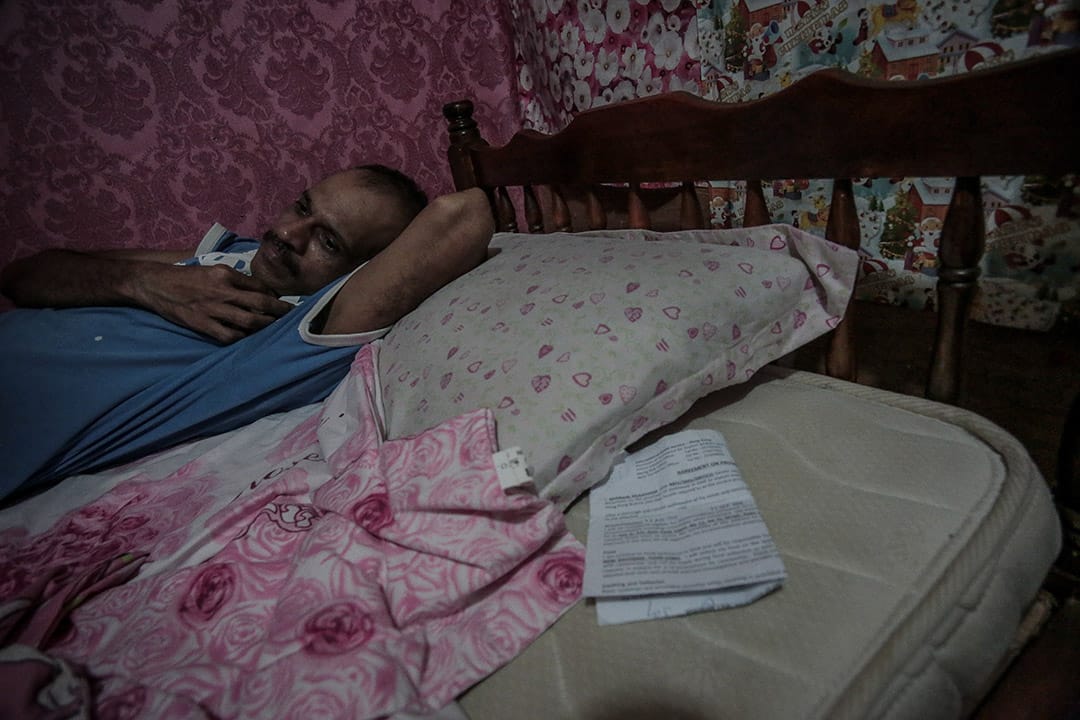 2013年，一位寻求庇护者在家中休息。香港的寻求庇护者持有的是一纸临时身份证明，他说，「行街纸」和住屋租约会长期随身携带，睡觉时则会放在枕头下，两纸证明对于自己来说尤其重要。摄: Billy H.C. Kwok/ 端传媒