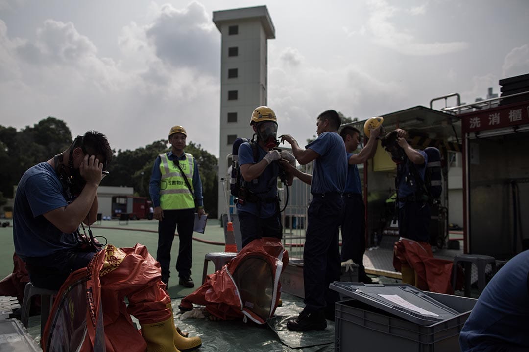 消防人員配戴裝備及穿上化學保護袍準備進行危害物質洩漏事故演習。攝：盧翊銘/端傳媒