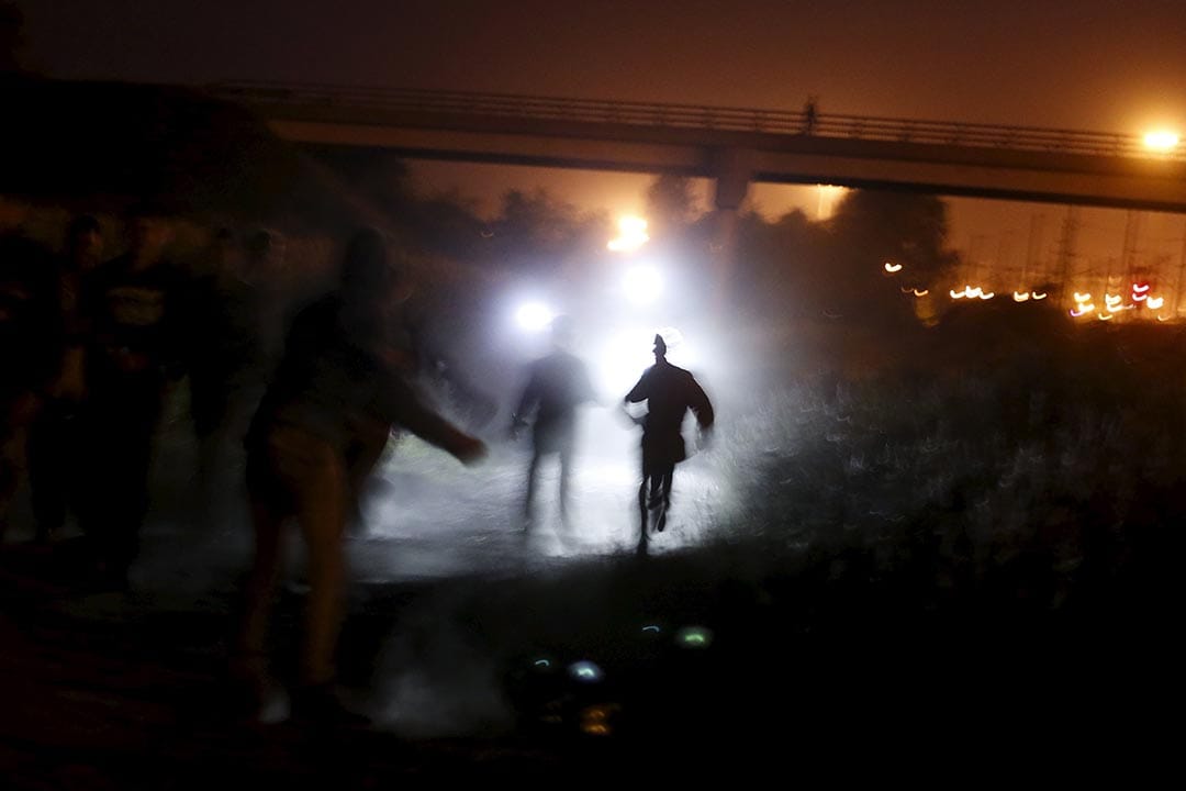 2015年8月5日 法國加來  警察手持電筒追捕企圖通過英法海底隧道偷渡的難民。攝: Juan Medina /REUTERS