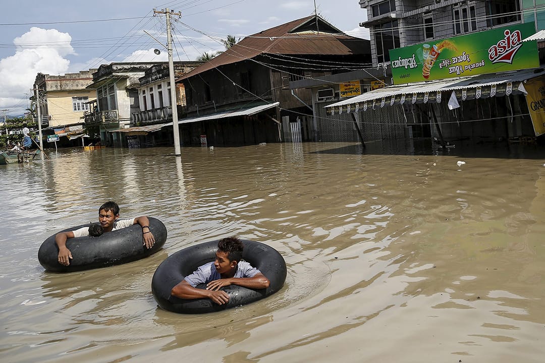 洪水淹没街道，灾民用水泡协助游出灾区。摄:  Soe Zeya Tun/REUTERS  