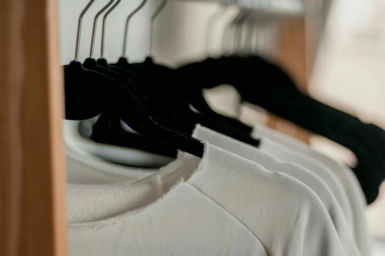 A wooden rack displaying several neatly hung white shirts.
