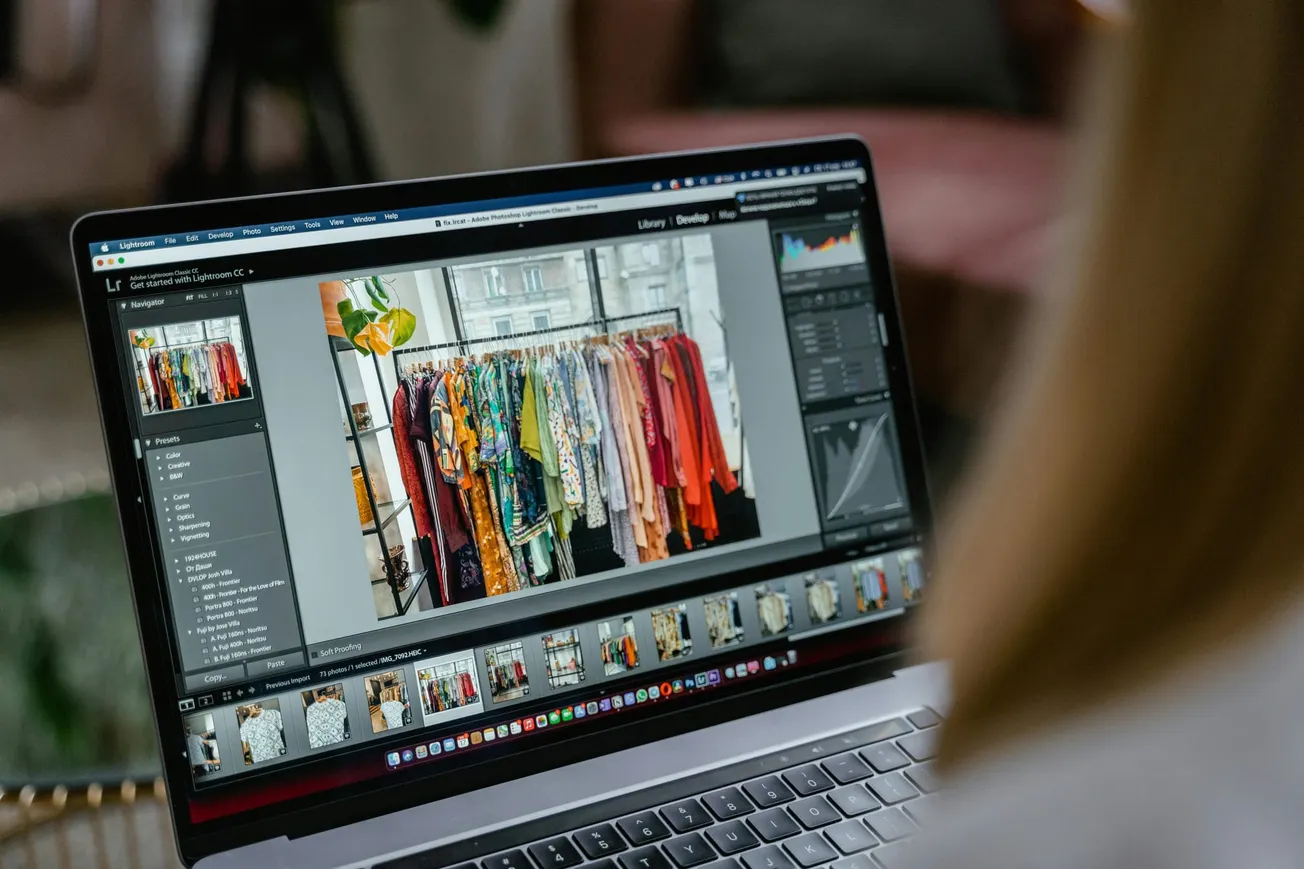 Laptop screen showing photo editing software with an image of colorful clothes on racks.