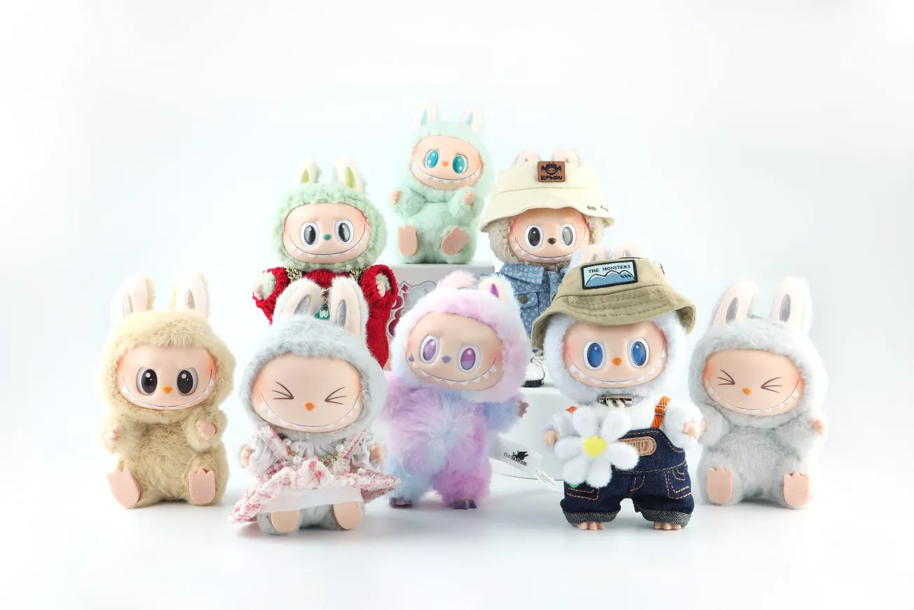 Eight Labubu toys with rabbit ears in various colorful costumes. They range from floral dresses to denim and pastel fuzzy outfits, exuding a playful and cheerful vibe.