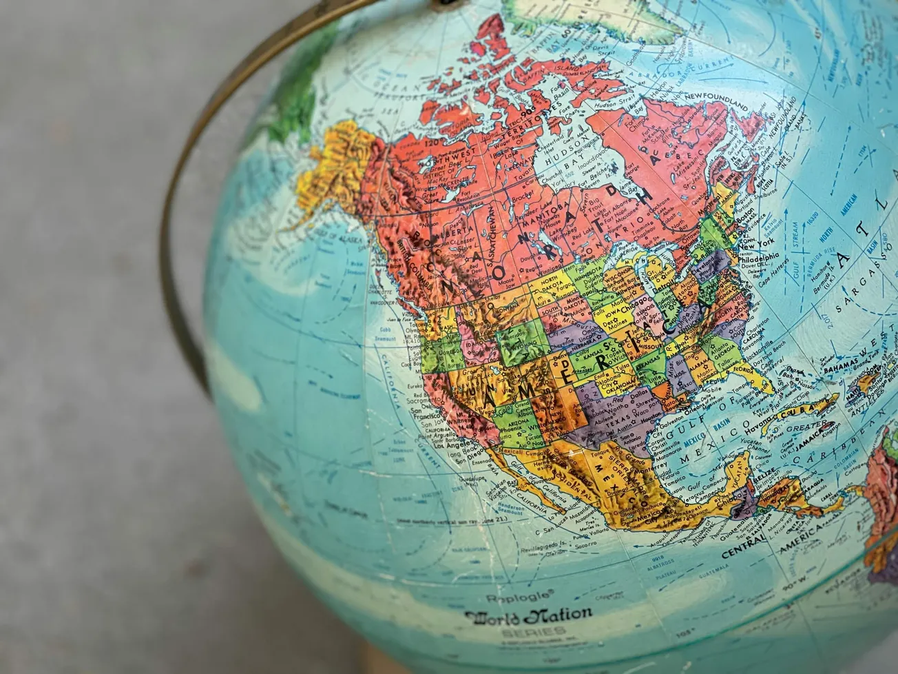 Close-up of a vintage globe showing North America. Countries and U.S. states are vividly colored, with the Atlantic Ocean visible on the right.