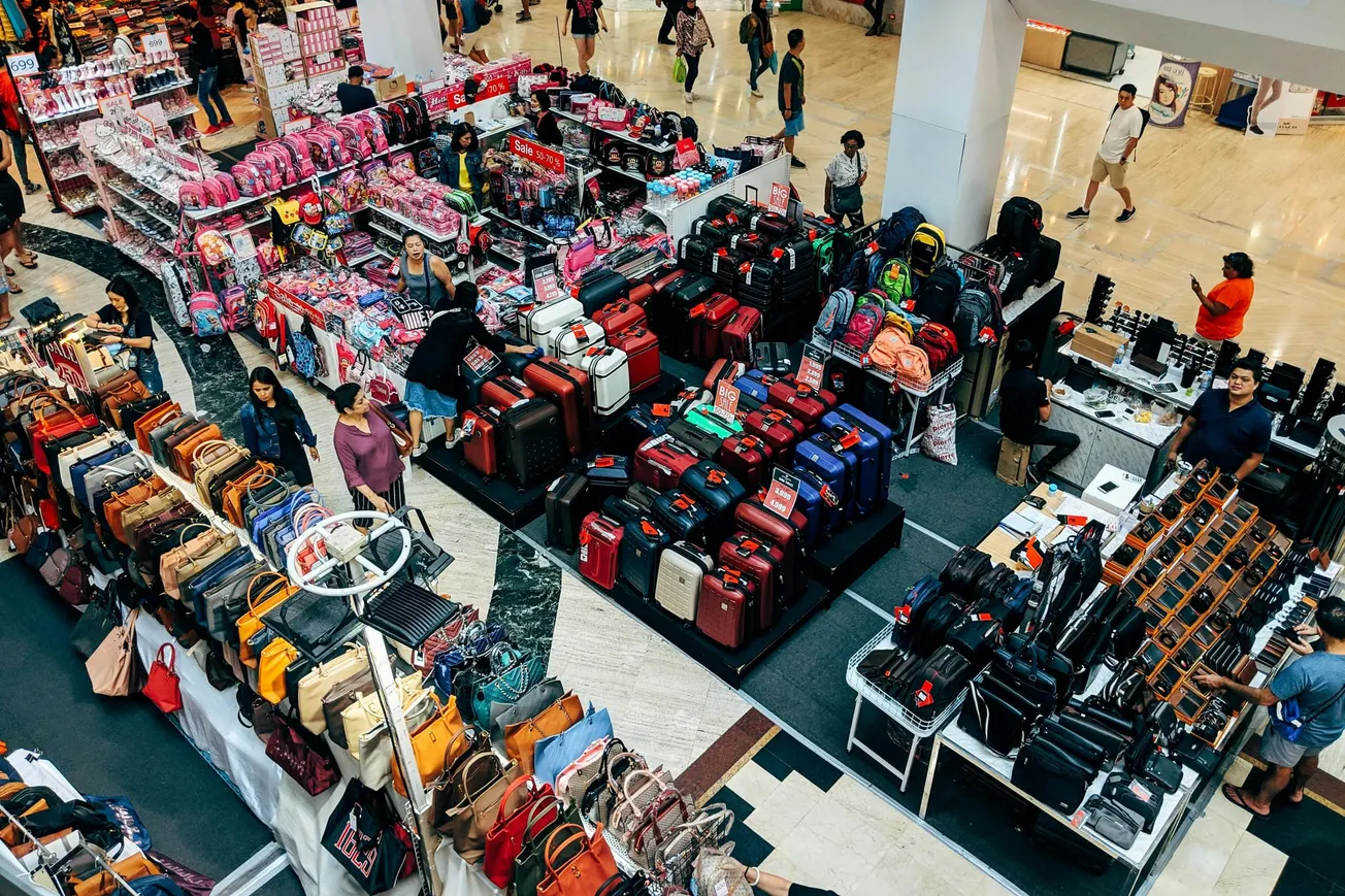 Aerial view of a bustling mall showcasing vibrant luggage displays, colorful handbags, and shoppers browsing various stalls.