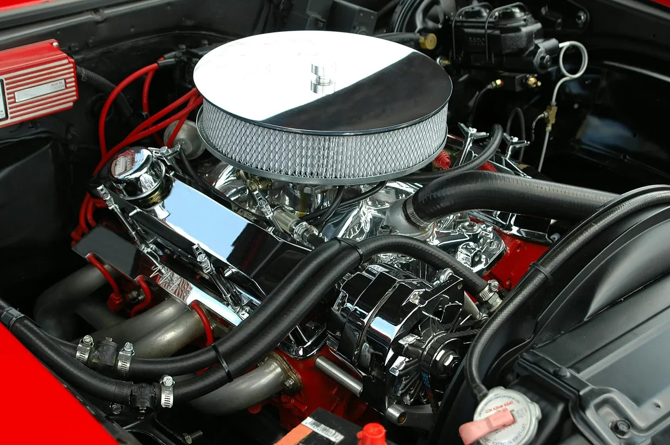 Close-up of a polished V8 car engine with chrome parts, red cables, and a shiny air filter. The scene conveys power and precision engineering.