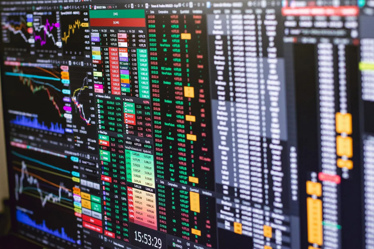 A computer screen displays complex stock market data, including colorful graphs and charts with numbers, conveying a busy and analytical atmosphere.