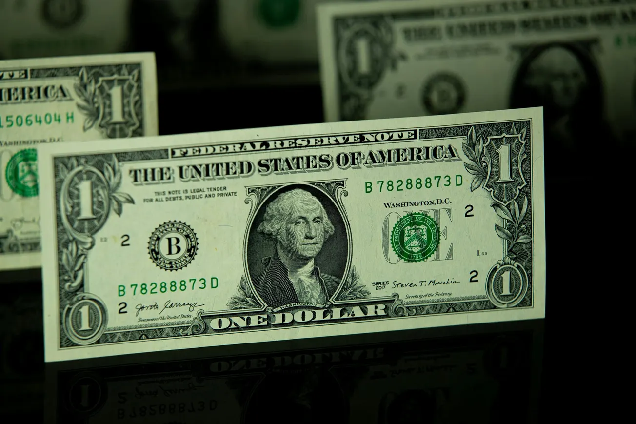 Close-up image of a U.S. one-dollar bill displaying George Washington's portrait, set against a dark background, emphasizing the green and black currency details.