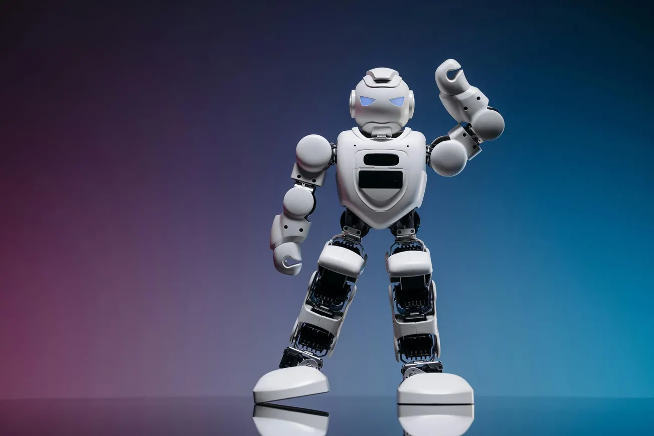 A humanoid robot with white armor stands confidently against a gradient background of purple and blue, raising a clenched fist. The mood is futuristic.