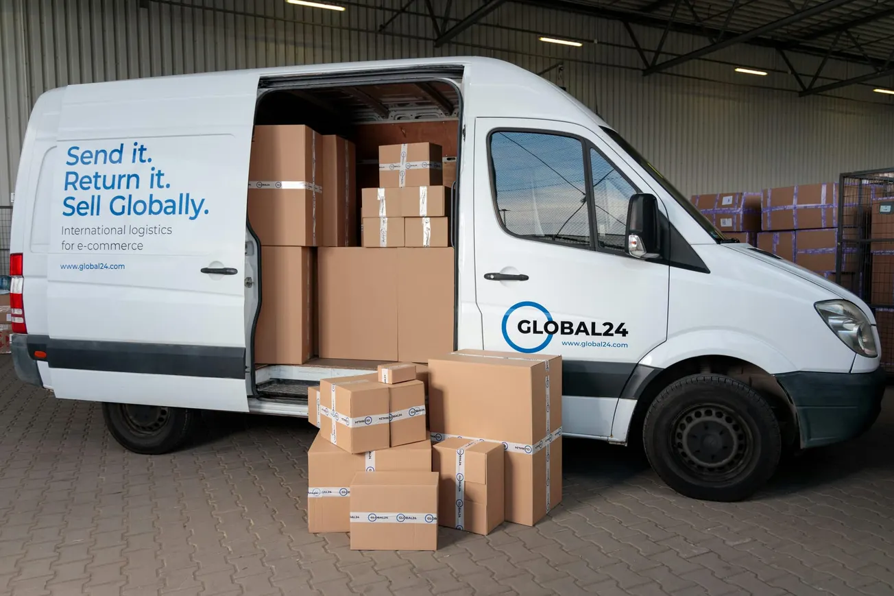 A white delivery van labeled "Global24" is parked with its side door open, showing stacks of cardboard boxes inside and outside, indicating logistics activity.