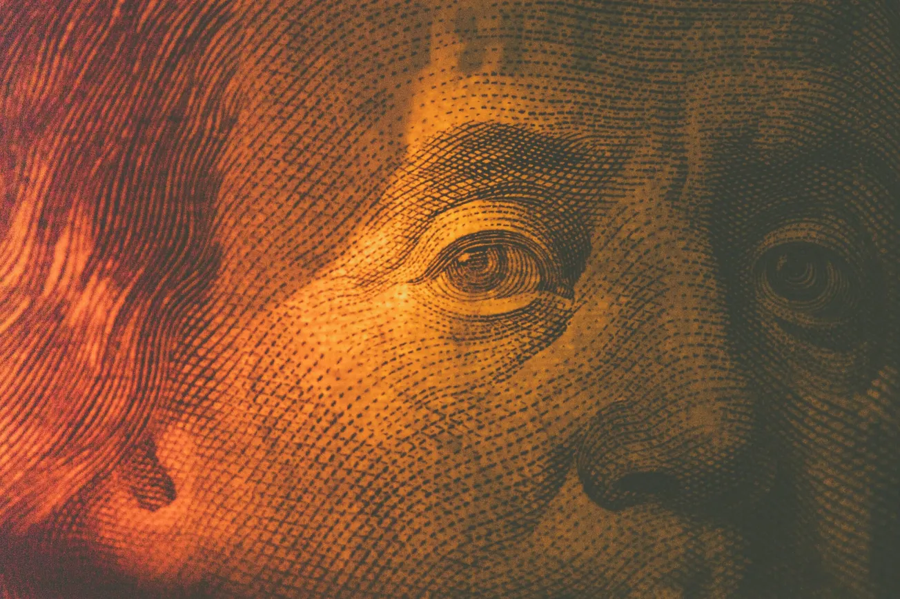 Close-up of a textured printed face, partially illuminated in warm orange light, highlighting intricate details and shadows conveying a vintage feel.